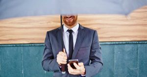 it-säkerhet. Man står under ett paraply och håller i en mobiltelefon